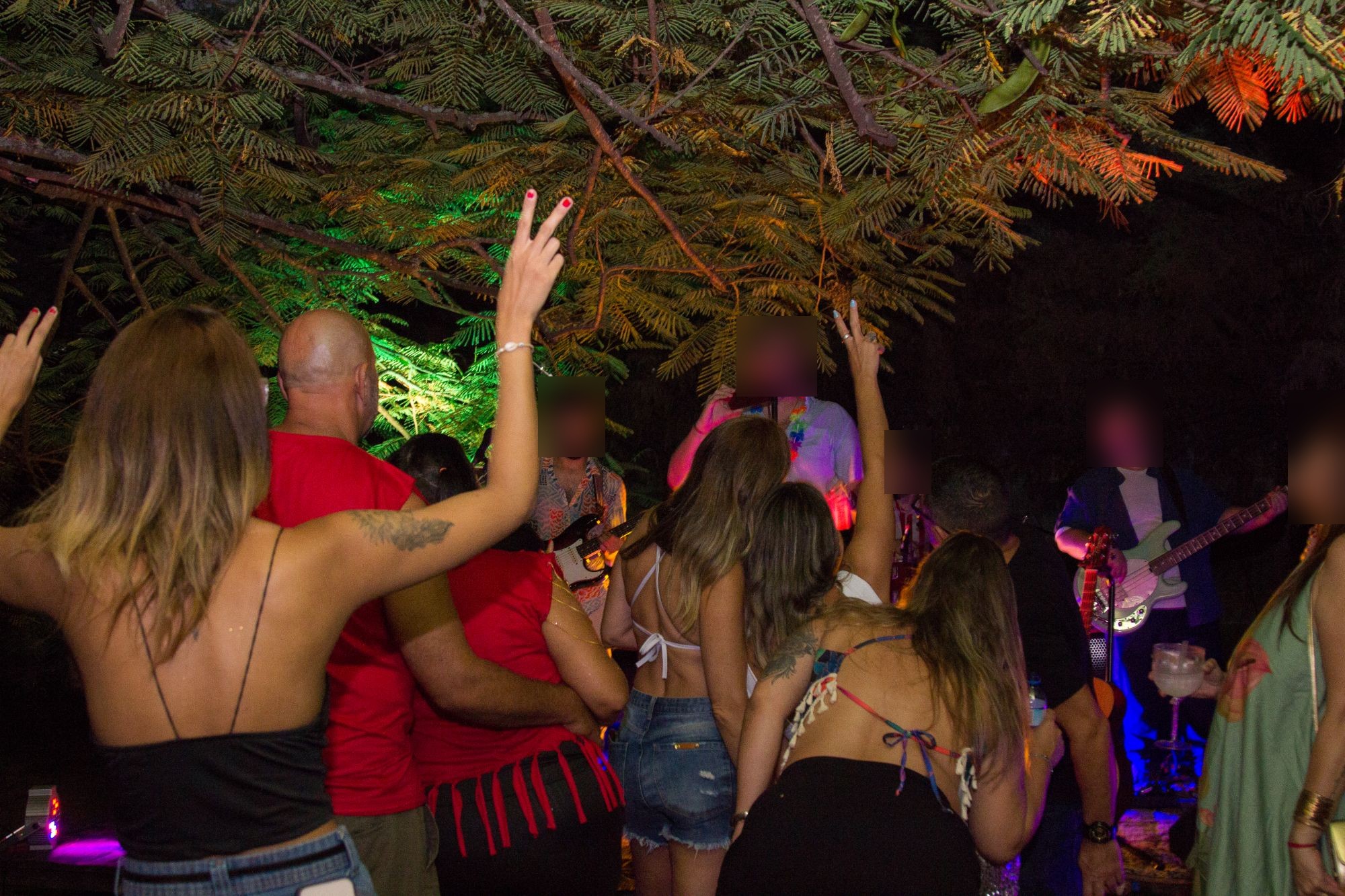 Banda tocando em palco ao ar livre, com público animado